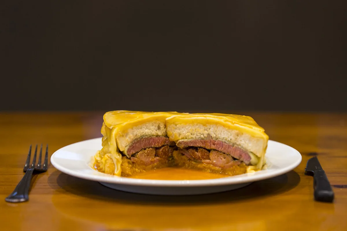 Close-up of layered Francesinha sandwich in Porto showing meat and sauce details