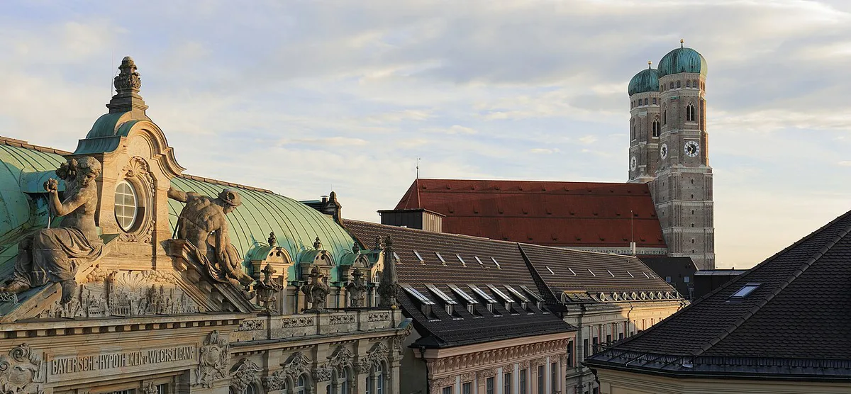 Spring blossom along a quiet Munich street with the Frauenkirche towers behind — 1