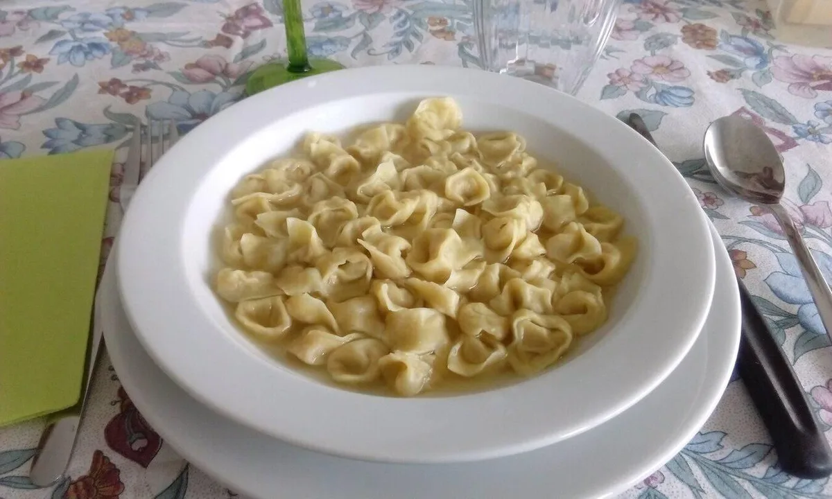 Fresh tagliatelle al ragù alongside sliced mortadella and Parmigiano on a wooden board in Bologna — 2
