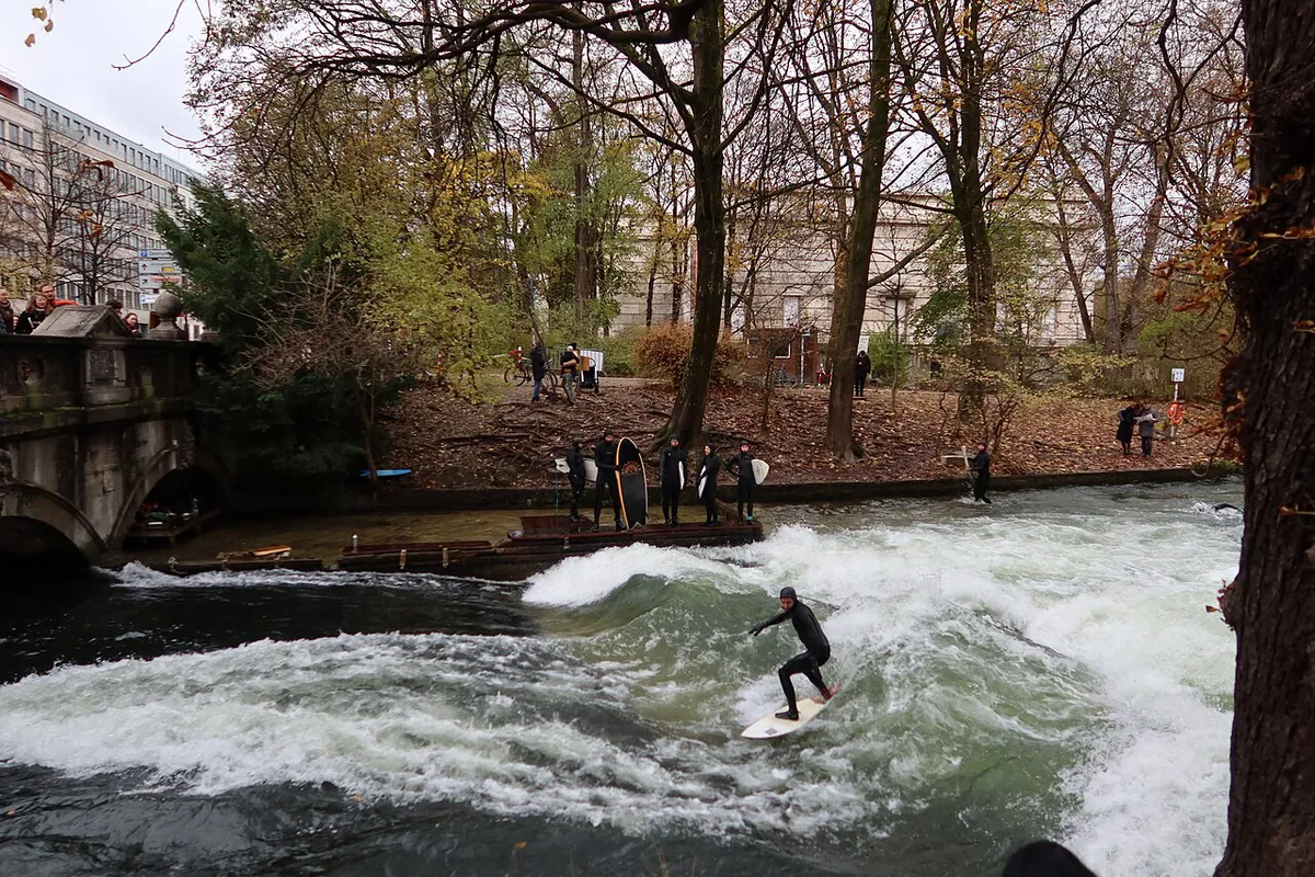 A surfer riding the standing Eisbach wave as onlookers watch in Munich — 1