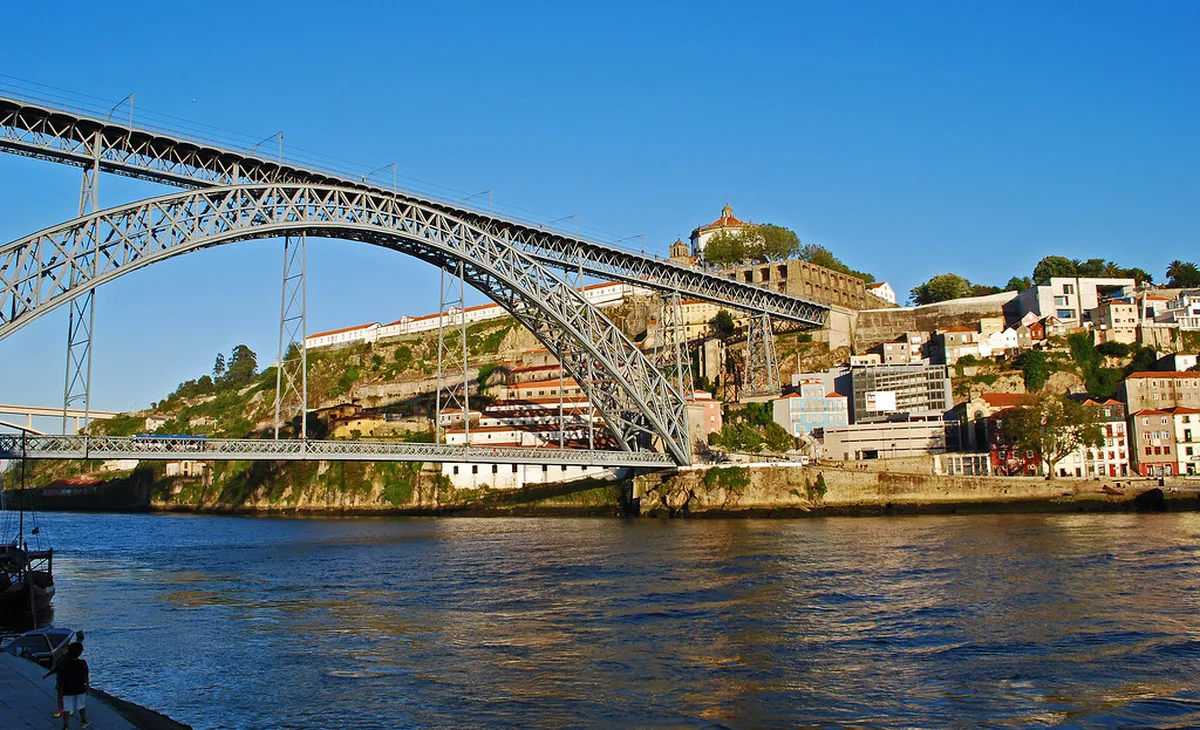 Dom Luis I Bridge spanning the Douro River valley in Porto with historic terraced buildings and the river below