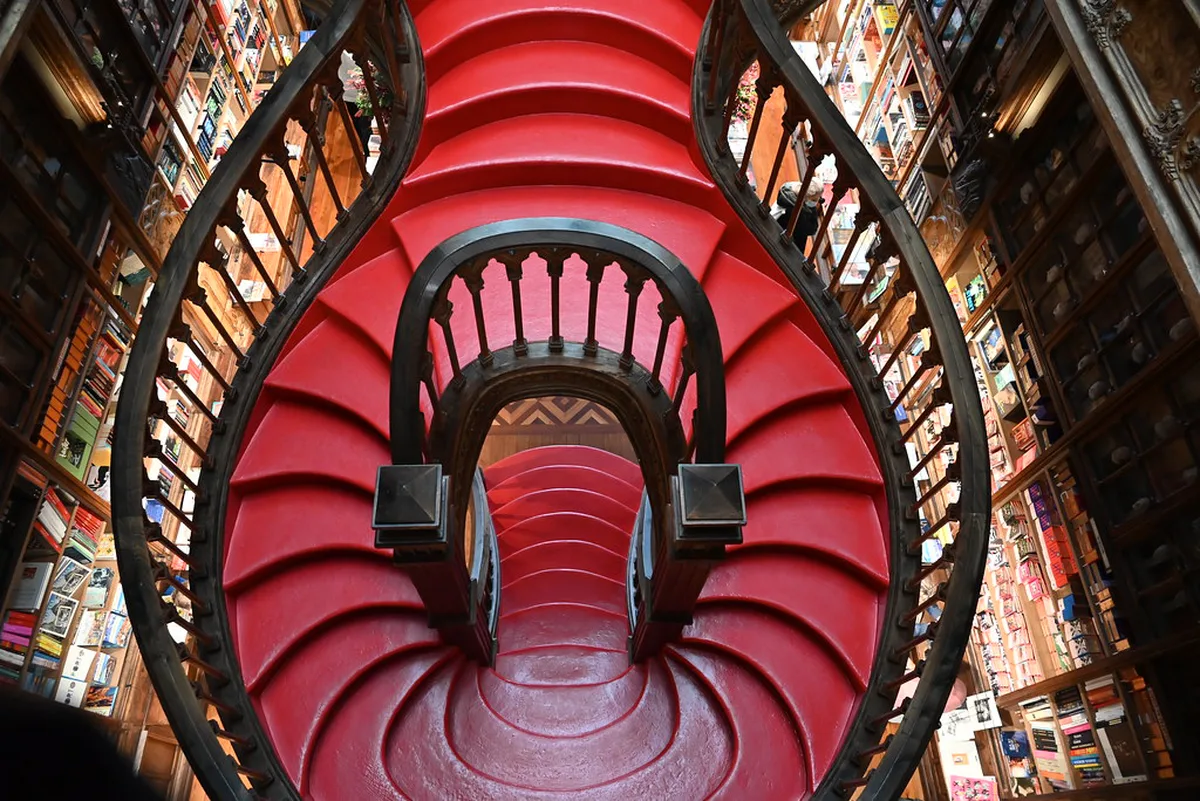 Ornate interior with carved wooden shelves and painted plaster details in Livraria Lello