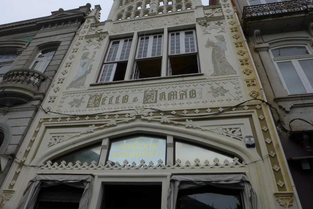 Neo-Gothic facade of Livraria Lello with painted figures representing Science and Art