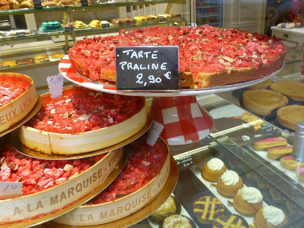 A pink praline tart alongside quenelle and cervelle de canut on a Lyon bouchon table — 2