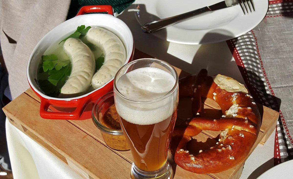 Weisswurst with sweet mustard and a pretzel on a Bavarian table — 1