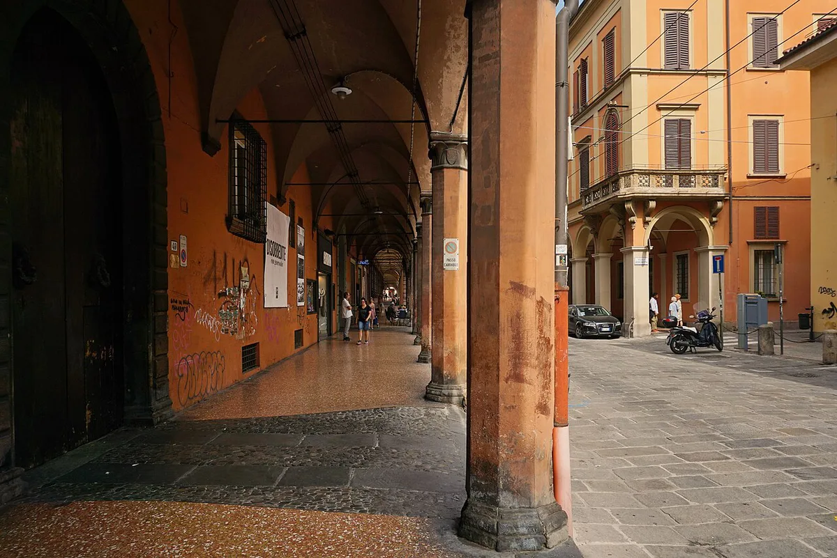 Rows of covered stone porticoes lining a historic street in central Bologna — 1