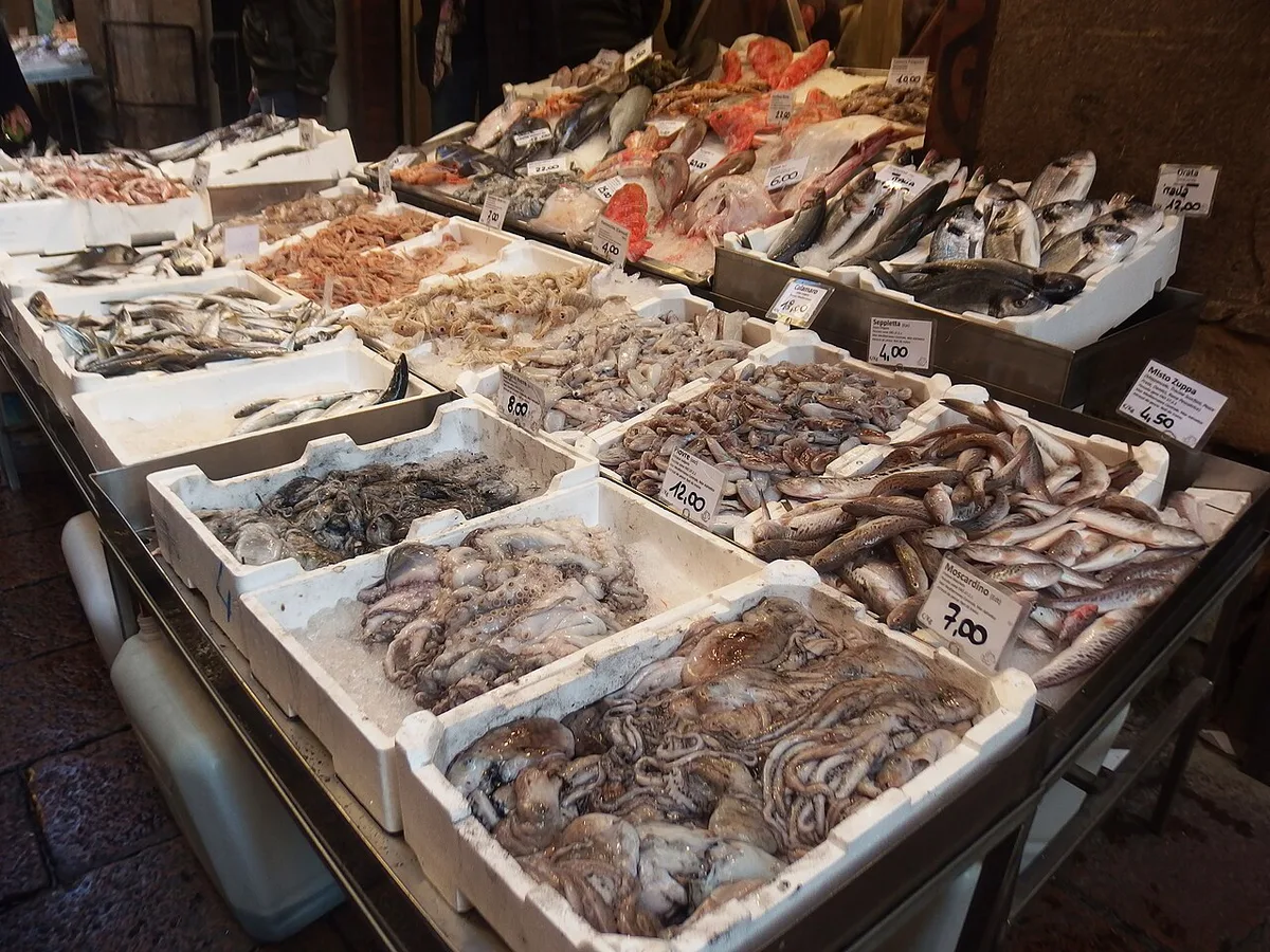 Fresh produce and salumi stalls lining Via Pescherie Vecchie in Bologna's Quadrilatero market — 1
