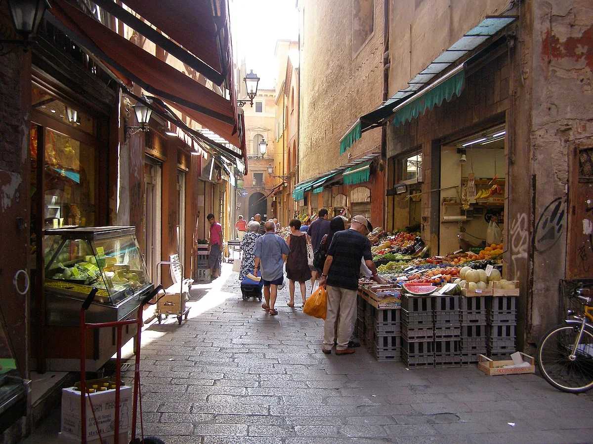 Fresh produce and salumi stalls lining Via Pescherie Vecchie in Bologna's Quadrilatero market — 2